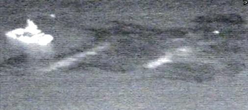 Prise depuis un hélicoptère, image infrarouge du navire dispersant de nuit une nappe de pétrole.